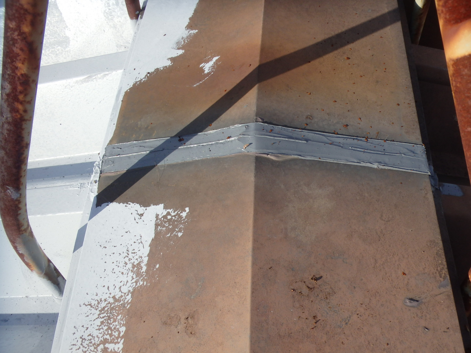 春日井市の社員寮、折板屋根の棟板金のシーリング打替えと折板屋根の下塗り作業