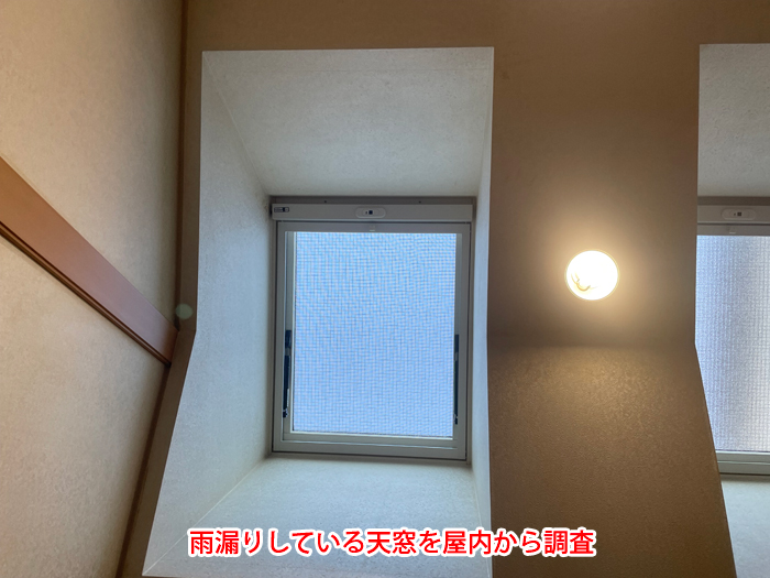 雨漏りしている天窓を屋内から調査している写真」
