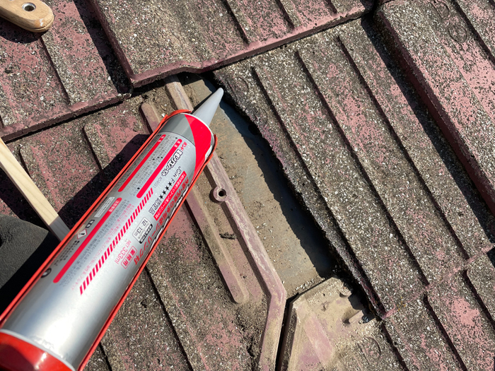 割れたモニエル瓦にコーキング材を充填している様子