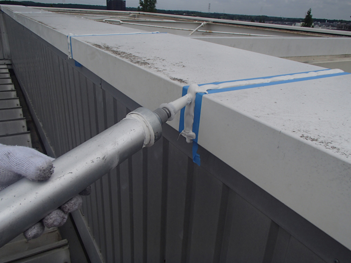 笠木のジョイント部にコーキング施工中の写真