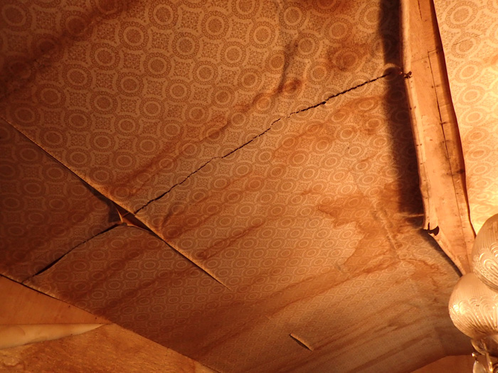天井に雨漏りのシミがあり、湿気でクロスが剥がれている